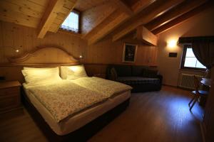 1 dormitorio con 1 cama y 1 sofá en una habitación en Hotel Tita Piaz, en Canazei