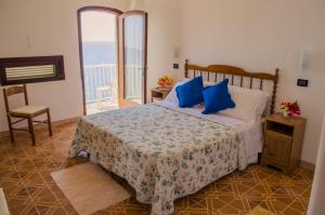 a bedroom with a bed with blue pillows and a balcony at Hotel Angelino in Ischia