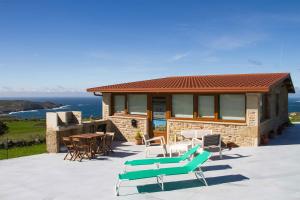 ein Haus mit einer Terrasse mit Stühlen und einem Tisch in der Unterkunft Casa Cabo Tourinan in Queiroso