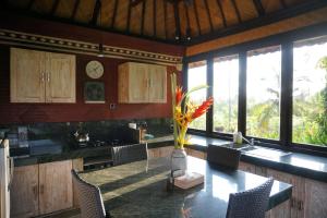 a kitchen with a table with chairs and a vase of flowers at Villa Gede Private Guest House in Selemadeg