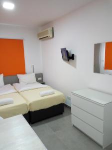 a room with two beds and a dresser in it at Elenapa Holiday Apartments in Ayia Napa
