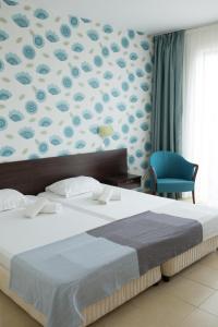 a bedroom with a large bed and a blue chair at Ema Hotel in Sozopol +28 photos