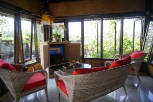 a living room with chairs and a table and windows at Villa Gede Private Guest House in Selemadeg