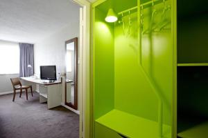 a room with a green wall and a white refrigerator at Campanile Bradford in Bradford