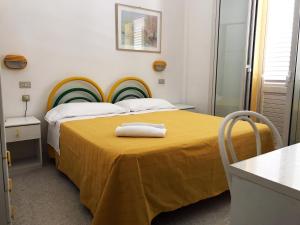 a hotel room with a bed with a yellow blanket at Hotel Vienna in Senigallia