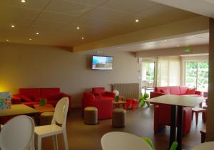 a waiting room with red chairs and tables at VVF Montpeyroux Auvergne in Parent