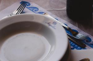 a white plate sitting on a table with a fork and knife at Hotel Angelino in Ischia