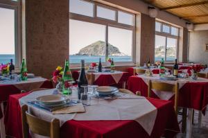 a restaurant with tables and chairs with a view of the ocean at Hotel Angelino in Ischia