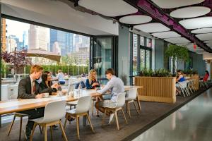 a group of people sitting at tables in a restaurant at YOTEL New York Times Square in New York