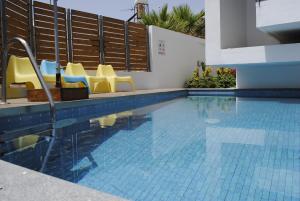 a swimming pool with yellow chairs and a swimming pool at Agnanti Apartments in Argaka