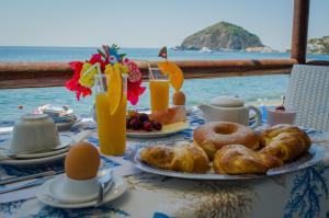 a table with a breakfast of pastries and orange juice at Hotel Angelino in Ischia