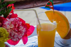 a glass of orange juice on a table with a flower at Hotel Angelino in Ischia