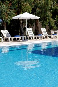 two chairs and an umbrella next to a swimming pool at Hotel Milton in Roda