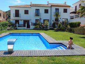 a boy sitting next to a swimming pool in front of a house at Casa Mirador los Bancales in Montejaque