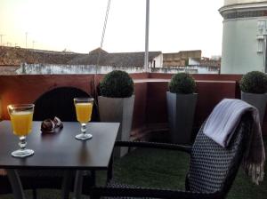 two glasses of orange juice on a table on a balcony at Life Apartments Quintana in Seville