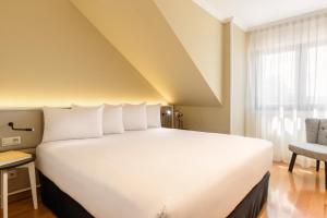 a large white bed in a room with a window at Apartamentos La Toja in Isla de la Toja