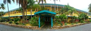 un edificio amarillo con palmeras y flores delante de él en Lindbergh Bay Hotel en Lindbergh Bay