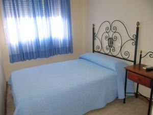 a bedroom with a bed with blue sheets and a window at Hostal El Gaitero in Arroyomolinos