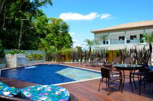 a swimming pool with chairs and a table next to a house at Hotel Bertell Inn in Penedo