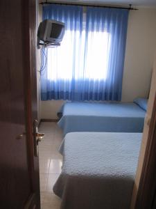 a small room with two beds and a window at Hostal El Gaitero in Arroyomolinos +3 photos