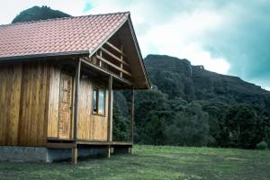 a small wooden house in a field with a mountain at Chalés Vista Bonita in Urubici
