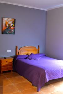 um quarto com uma cama com lençóis roxos e uma cómoda em Casa Alonso em Narón