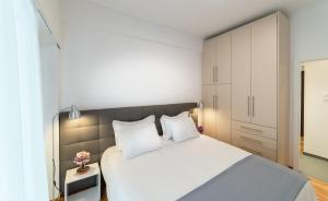 雅典的住宿－近雅典衛城的現代化設計公寓，卧室配有一张白色大床和白色橱柜。
