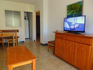 una sala de estar con TV de pantalla plana en una cómoda de madera en CYE 5 Rentalmar, en La Pineda