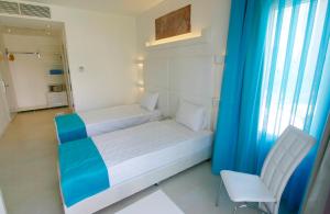 a small bedroom with a bed and a chair at Costa Luvi Hotel Bodrum - All Inclusive in Gümbet