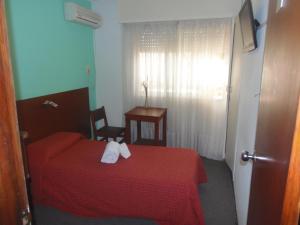 1 dormitorio con 1 cama roja y 2 toallas en Hotel Central, en Durazno