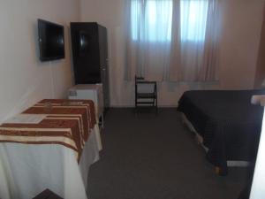 a hotel room with two beds and a flat screen tv at Hotel Central in Durazno