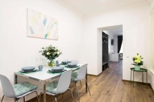 - une salle à manger blanche avec une table et des chaises blanches dans l'établissement St.Roland Livu Square, à Riga