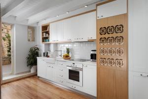a kitchen with white cabinets and a wooden door at Aeria Apartments in Chania