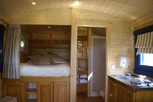 - une chambre dans une cabane en rondins avec un lit et un lavabo dans l'établissement La Roulotte du Domaine de Meigné, à Meigné