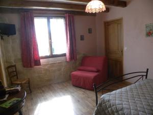 1 dormitorio con cama, silla roja y ventana en Auberge les Volpilières, en Ruynes-en-Margeride