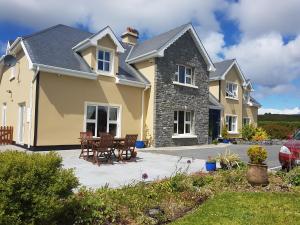 een geel huis met een tafel en stoelen bij Greenlawn Lodge in Lisdoonvarna