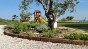 einen Spielplatz mit einem Baum und einer Rutsche in der Unterkunft Country House Ciliegia Rossa in Colonnella