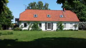 ein weißes Haus mit orangefarbenem Dach auf einem Hof in der Unterkunft Villa Signedal Hostel in Kvidinge