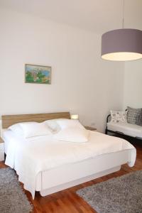 a white bedroom with a white bed and a lamp at Central House Nona in Crikvenica