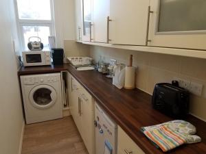 a kitchen with a washing machine and a microwave at Dawlish Sea View Apartment in Dawlish