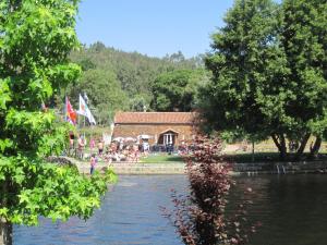 ein Haus neben einem Wasserkörper mit Flaggen in der Unterkunft Casa do Retiro in Pedrógão Grande