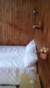 1 dormitorio con cama blanca y pared de madera en Sunshine, en Gramado