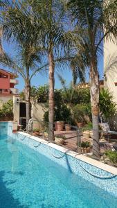 a swimming pool with palm trees next to a house at Villa Mosè Apartment in Villaggio Mosè