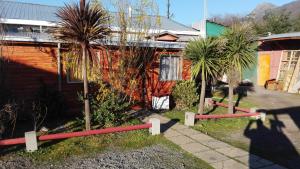 a fence in front of a house with palm trees at Puelche de Antuco in Antuco +10 photos