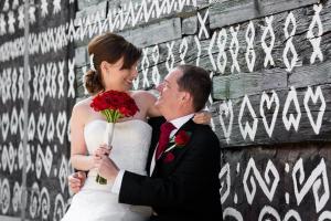 a bride and groom are standing next to a wall at Penzion Javorina in Čičmany