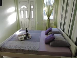 a bedroom with two beds with purple pillows and a bottle of wine at Apartments Perla in Biograd na Moru