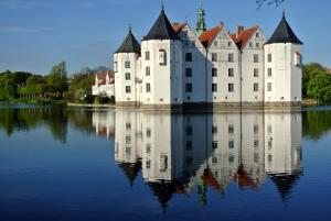 a castle on a lake with its reflection in the water at Haus Nordlys in Glücksburg