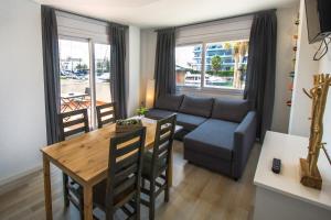 Vista Roses Mar - Apartamento con Piscina في روساس: غرفة معيشة مع طاولة وأريكة وغرفة طعام