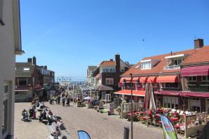 a street in a town with people sitting on tables at La Tulipe in Egmond aan den Hoef