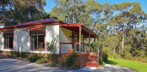 a small white house with a red roof at Araluen Park Cottages in Lakes Entrance